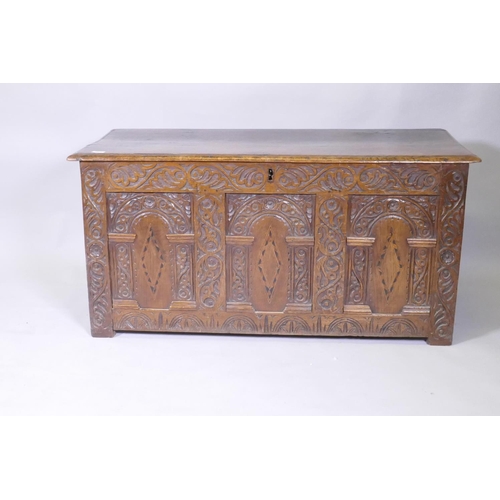 1035 - An C18th oak coffer with plank top and triple panel front with carved and inlaid panels, and applied... 