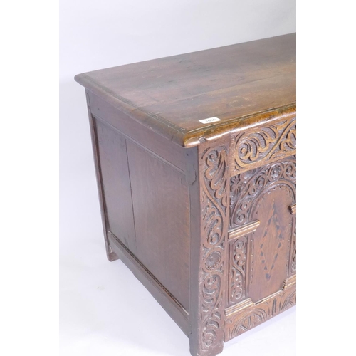 1035 - An C18th oak coffer with plank top and triple panel front with carved and inlaid panels, and applied... 