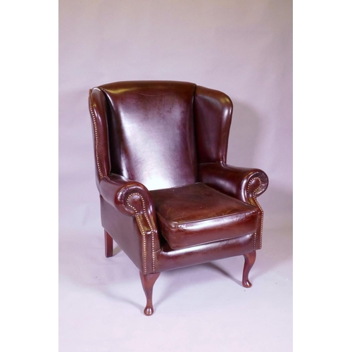 1039 - A brown leather wing back armchair, 106cm high