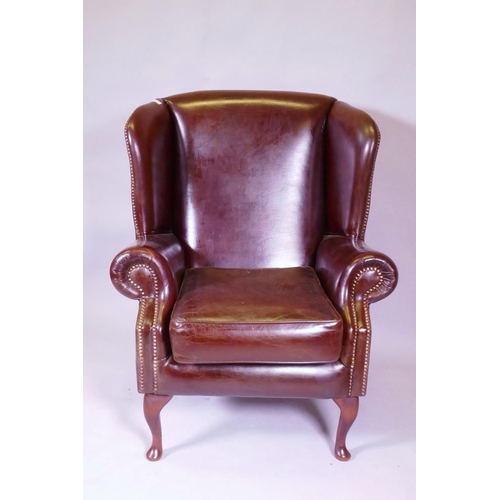 1039 - A brown leather wing back armchair, 106cm high