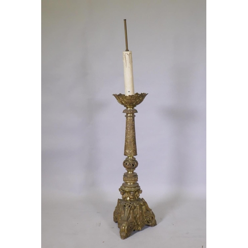 1056 - A gilt brass church torchere/pricket candlestick, decorated in relief with demons and angels, 144cm ... 