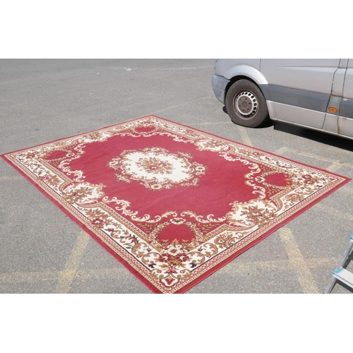 1066 - A large oriental red ground carpet with a cream floral medallion and borders, 240 x 330cm