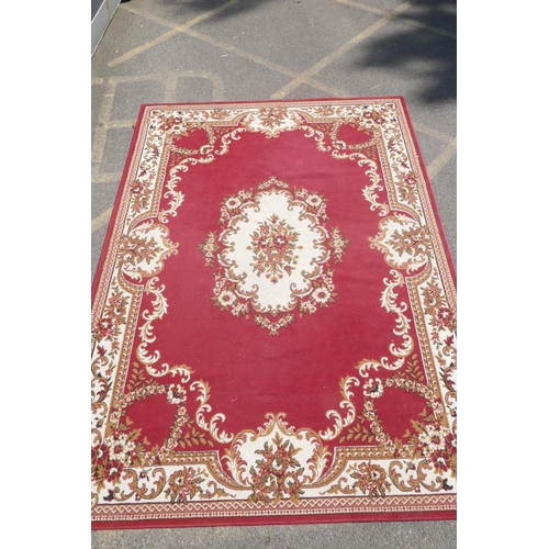 1066 - A large oriental red ground carpet with a cream floral medallion and borders, 240 x 330cm