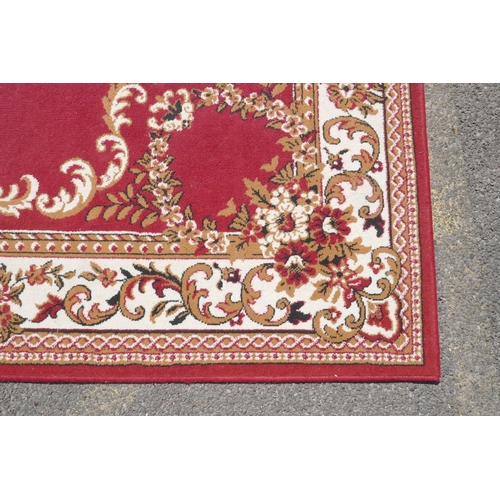 1066 - A large oriental red ground carpet with a cream floral medallion and borders, 240 x 330cm