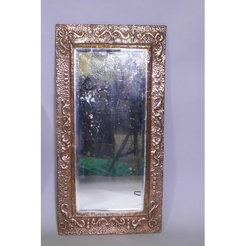 1069 - An antique Arts & Crafts copper mirror with repousse decoration, and a circular gilt wall mirror... 