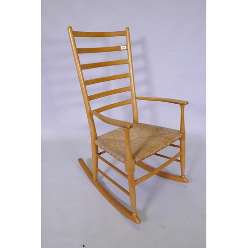 1118 - A beech wood ladder back rocking chair with rush seat