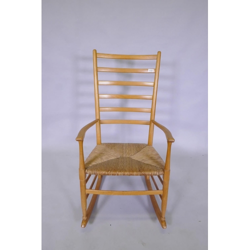 1118 - A beech wood ladder back rocking chair with rush seat