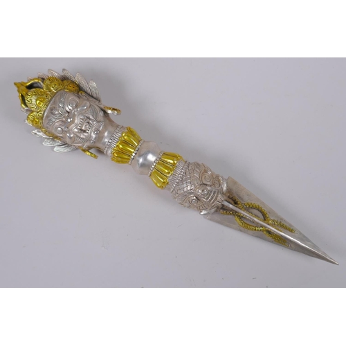 133 - A Tibetan white metal phurba, the handle decorated with the mask of a wrathful deity, 32cm long