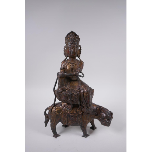 135 - A Sino Tibetan filled gilt bronze Buddha, seated on the back of a mythical creature, 32cm high