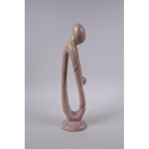 137 - A Kenyan carved and polished Kisii stone figure group in the form of a mother and child, 23cm high