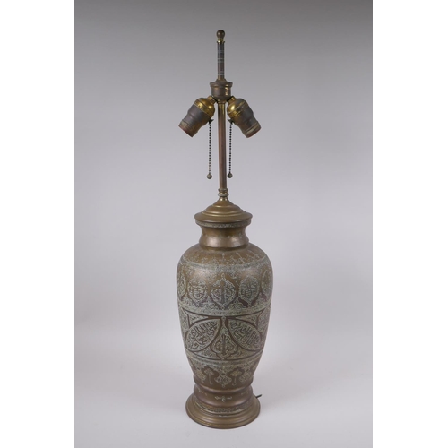 157 - An Islamic brass vase with chased script decoration, converted to a table lamp, 67cm high