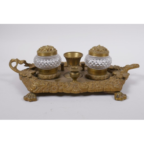 21 - An antique brass desk stand with raised vine decoration and two glass inkwells, 30 x 20cm