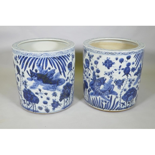 31 - A pair of Chinese blue and white porcelain cylinder jardinieres decorated with carp in a lotus pond,... 