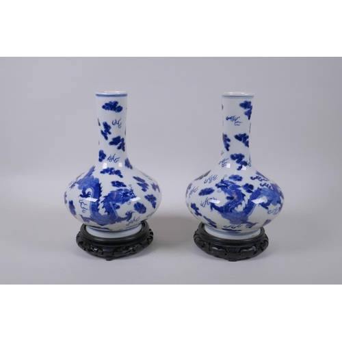 59 - A pair of blue and white porcelain vases with dragon decoration, on carved hardwood stands, Chinese ... 