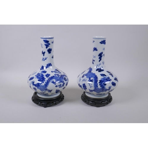 59 - A pair of blue and white porcelain vases with dragon decoration, on carved hardwood stands, Chinese ... 