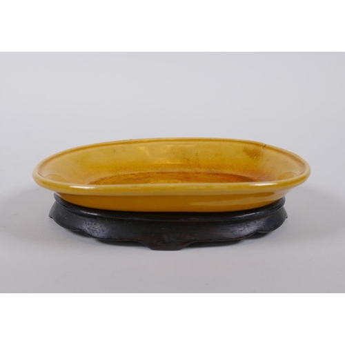 65 - A Chinese yellow ground porcelain dish with incised dragon decoration, on a hardwood stand, 12 x 9cm