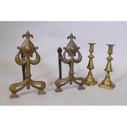 88 - A pair of C19th Art Nouveau fire dogs, 32cm high and a pair of brass candlesticks