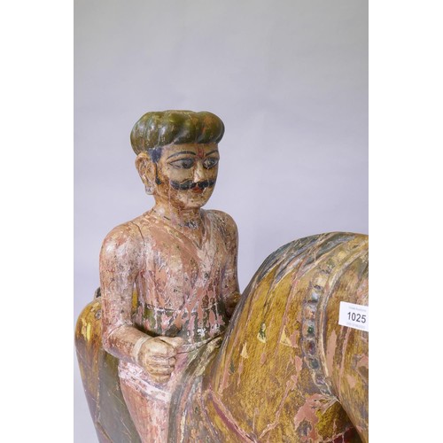 1025 - A carved and painted Indian figure of a mounted horseman, mounted on a base with wheels, 110cm high,... 