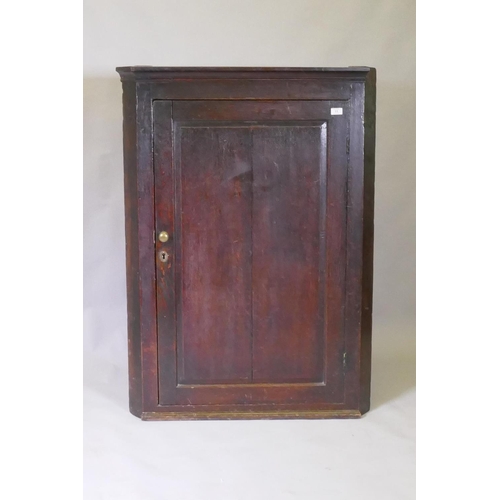 1040 - A Georgian oak hanging corner cupboard, fielded panel door and shaped shelves, 90 x 124cm