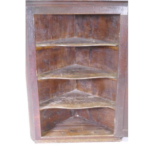 1040 - A Georgian oak hanging corner cupboard, fielded panel door and shaped shelves, 90 x 124cm