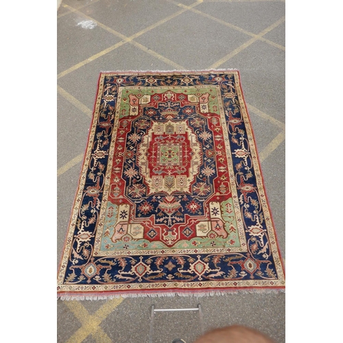 1055 - A Kazak Caucasian multicolour ground wool rug with a central medallion design and blue borders, 224 ... 