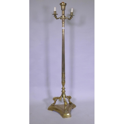 1062 - A brass floor lamp with three branches and fluted column, raised on three paw supports, 142cm high