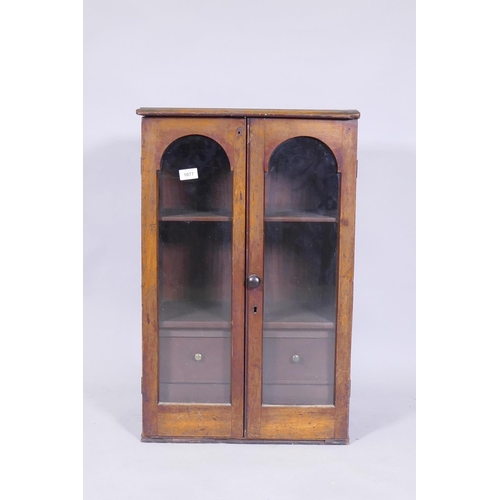 1077 - A Victorian mahogany hanging wall cupboard with two arched glazed doors, fitted with shelves and fou... 