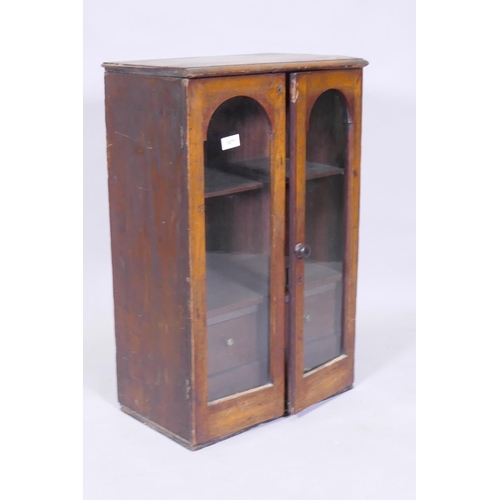 1077 - A Victorian mahogany hanging wall cupboard with two arched glazed doors, fitted with shelves and fou... 