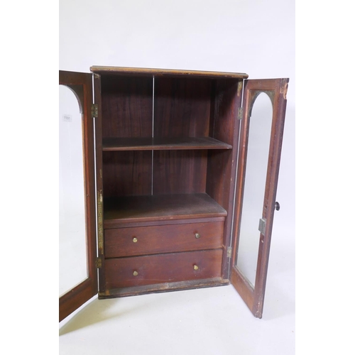 1077 - A Victorian mahogany hanging wall cupboard with two arched glazed doors, fitted with shelves and fou... 