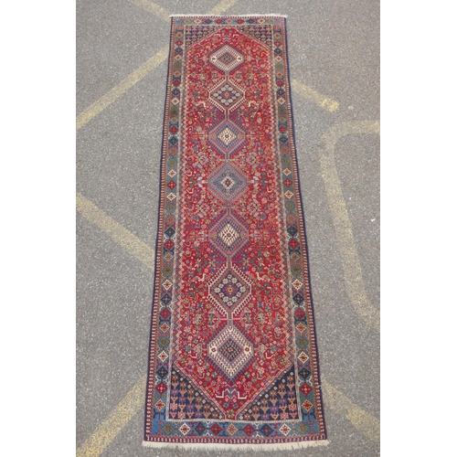 1089 - A south Persian Ghashgai red ground wool runner, decorated with a string of medallions, birds and fl... 