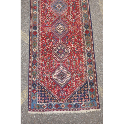 1089 - A south Persian Ghashgai red ground wool runner, decorated with a string of medallions, birds and fl... 