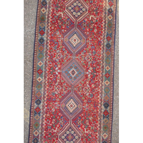 1089 - A south Persian Ghashgai red ground wool runner, decorated with a string of medallions, birds and fl... 