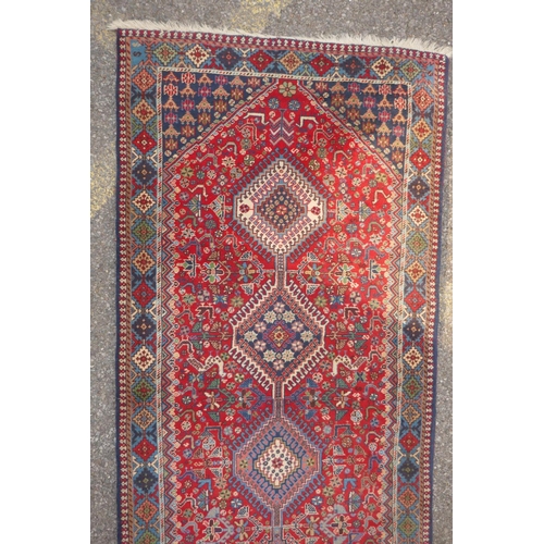 1089 - A south Persian Ghashgai red ground wool runner, decorated with a string of medallions, birds and fl... 