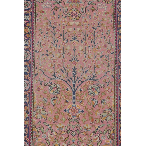 1090 - An antique Turkish pink ground wool rug with tree of life design, 82 x 130cm