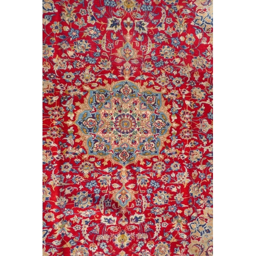 1091 - An Iranian red ground wool Isfahan carpet, with floral medallion design and blue borders, 275 x 375c... 