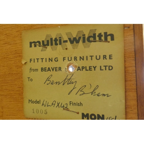 1096 - A mid century Beaver & Tapley Ltd multi width teak unit in two sections, the upper with sliding ... 