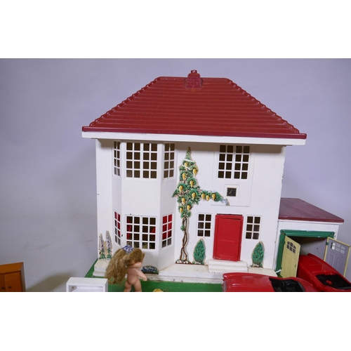 14 - A mid century doll's house with sliding metal front, illuminated and with furnishings, mounted on a ... 