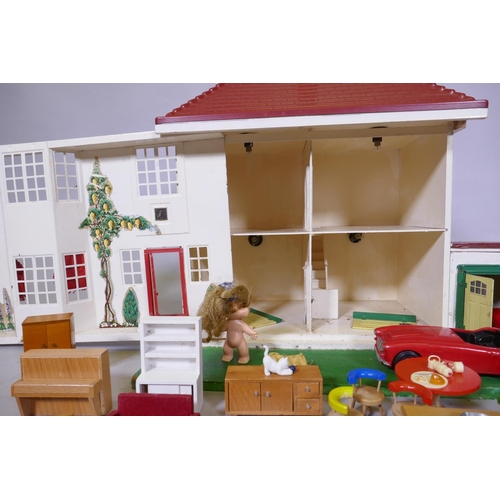 14 - A mid century doll's house with sliding metal front, illuminated and with furnishings, mounted on a ... 