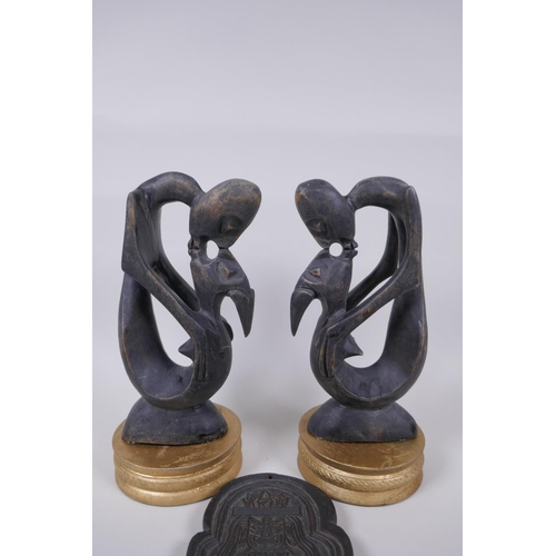 72 - A pair of African carved hardwood figure groups, and a Tibetan carved wood plaque, largest 28cm high