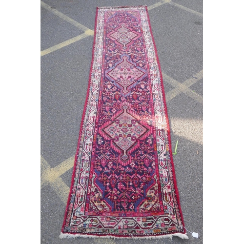 1117 - A Persian red ground wool runner with multi colour geometric medallion design, 85 x 340cm