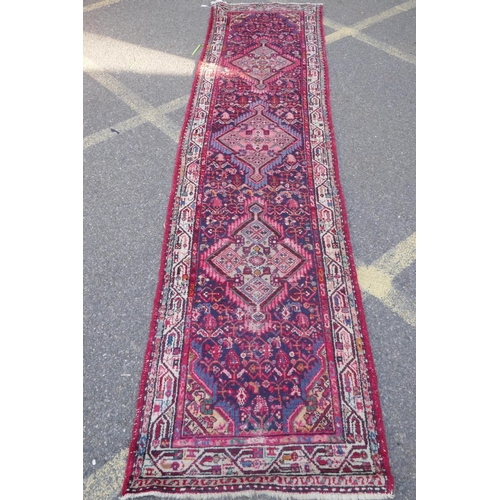 1117 - A Persian red ground wool runner with multi colour geometric medallion design, 85 x 340cm