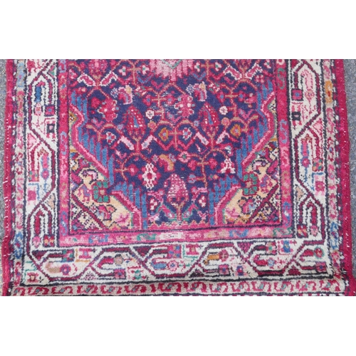 1117 - A Persian red ground wool runner with multi colour geometric medallion design, 85 x 340cm