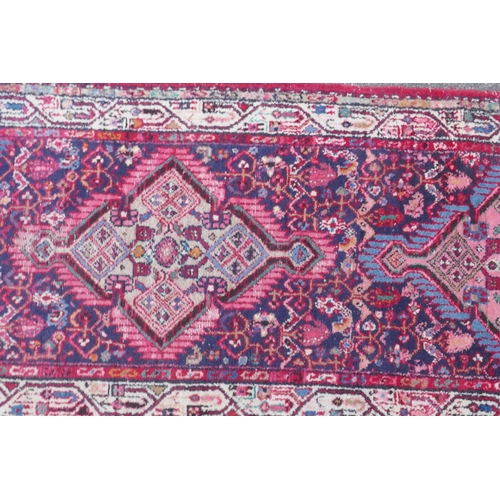 1117 - A Persian red ground wool runner with multi colour geometric medallion design, 85 x 340cm