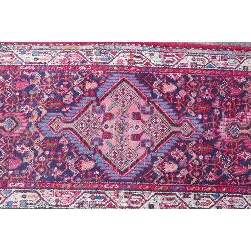 1117 - A Persian red ground wool runner with multi colour geometric medallion design, 85 x 340cm