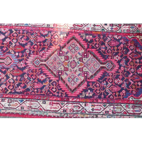 1117 - A Persian red ground wool runner with multi colour geometric medallion design, 85 x 340cm