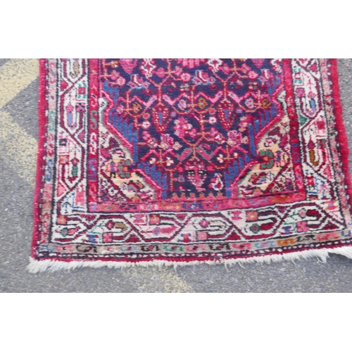 1117 - A Persian red ground wool runner with multi colour geometric medallion design, 85 x 340cm