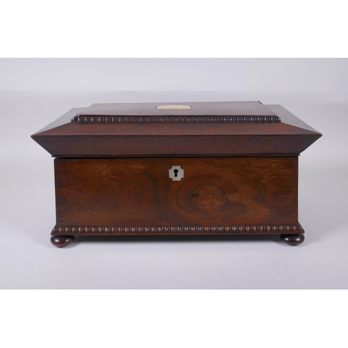 12 - An antique rosewood sarcophagus shaped tea caddy with mother of pearl inlay, two handles and bun fee... 