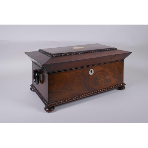 12 - An antique rosewood sarcophagus shaped tea caddy with mother of pearl inlay, two handles and bun fee... 