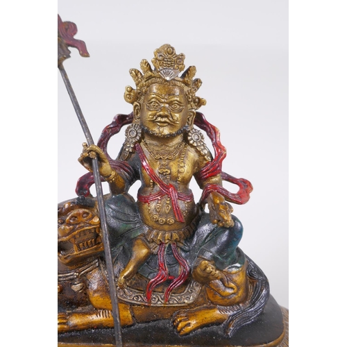 129 - A Sino Tibetan cold painted bronze of a wrathful deity seated on a the back of a kylin, 4 character ... 