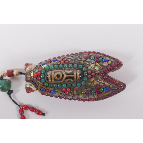 130 - A Tibetan iron toggle in the form of a cicada, the wings set with a dzi bead, abalone, coral and har... 